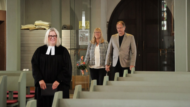 Ein Paar zieht zusammen mit der Pfarrerin in der Kirche ein.